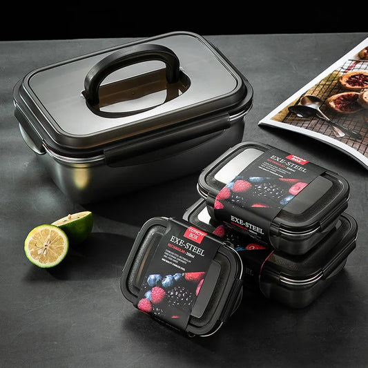 Black food containers with lids on a dark surface with a lime and leafy greens.