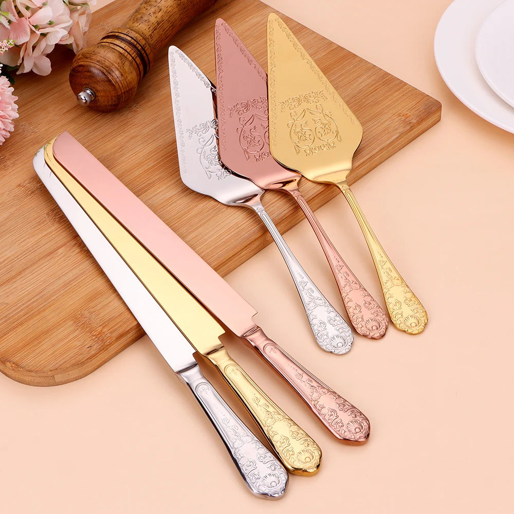 Set of three cake knives in gold, silver, rose gold, and pink on a wooden board.