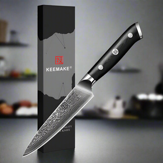 Knife with black handle and silver blade next to a KEEMAKE branded box on a white background