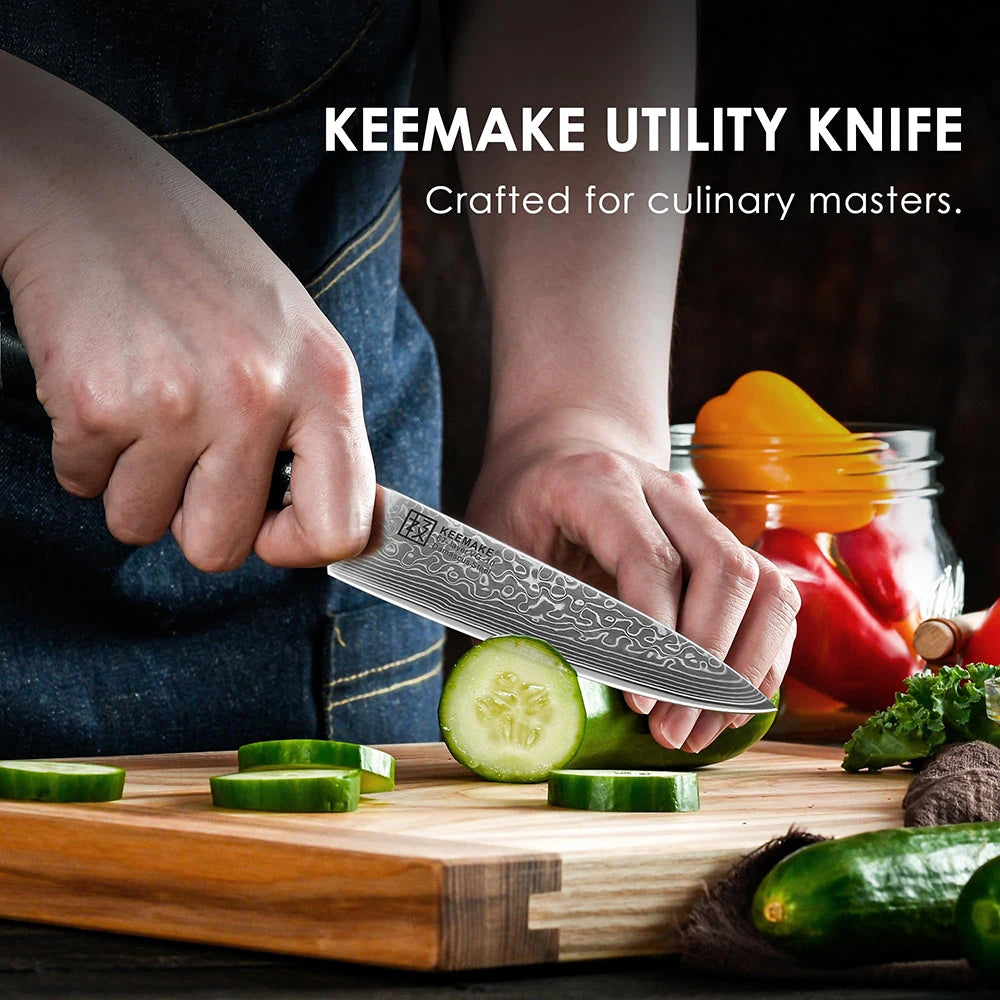 Person using a Keemake utility knife to cut cucumbers on a wooden cutting board with vegetables in the background.