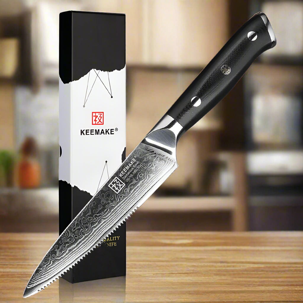 Serrated knife with black handle and detailed blade next to its packaging on a white background