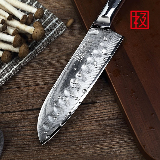 Chef's knife with water droplets on a wooden surface next to mushrooms