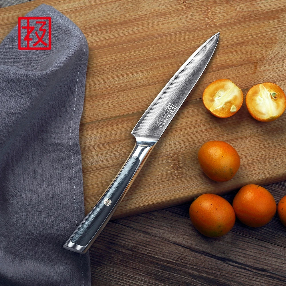Knife on a wooden cutting board with oranges and a gray cloth