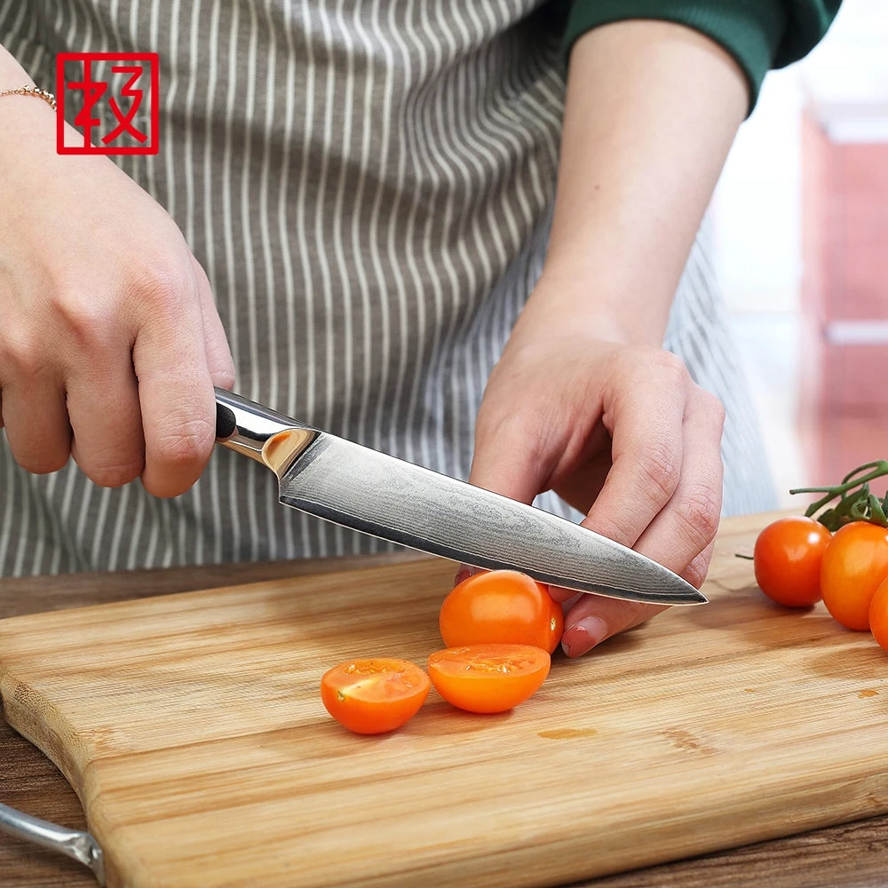 Person using a knife to cut cherry tomatoes on a wooden cutting board.
