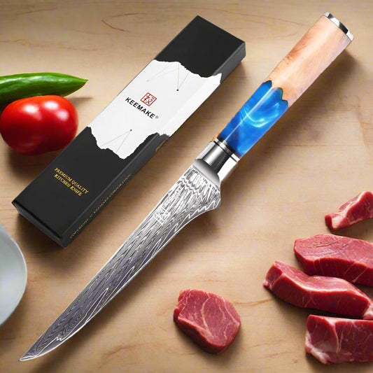 Forked knife with wooden handle and blue accent, next to its packaging and fresh vegetables on a white background