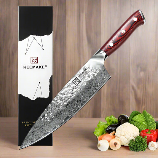 Keemake chef's knife with a red handle next to its packaging and a display of vegetables.
