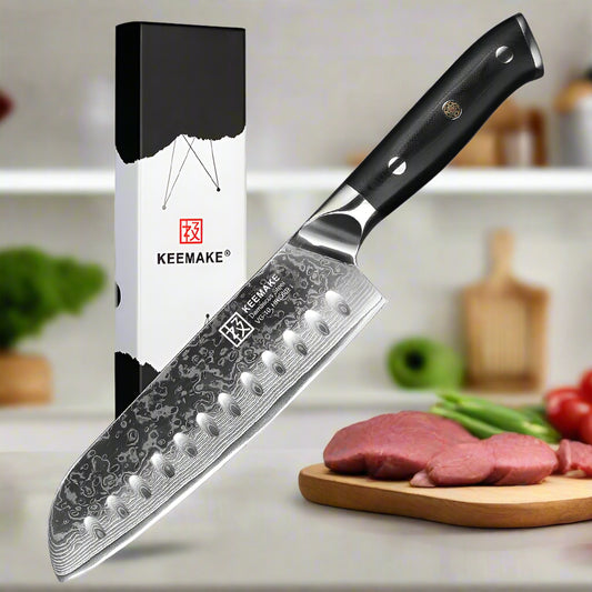 Keemake chef's knife with black handle and detailed blade design, next to its packaging on a white background.