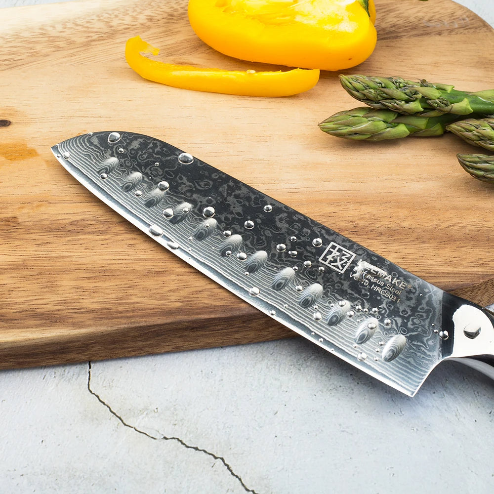 Chef's knife with Damascus pattern on a wooden cutting board with vegetables