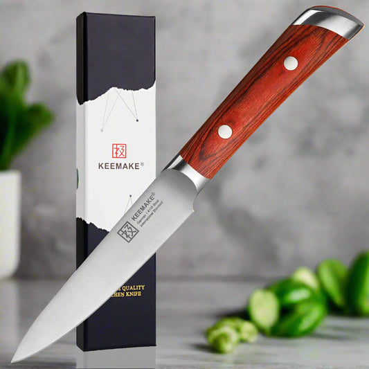 Chef's knife with red wooden handle and silver blade next to its packaging on a white background
