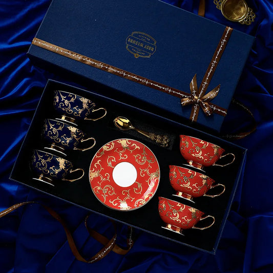 Set of red and blue ceramic cups and saucers with a decorative plate in a gift box on a blue satin background.