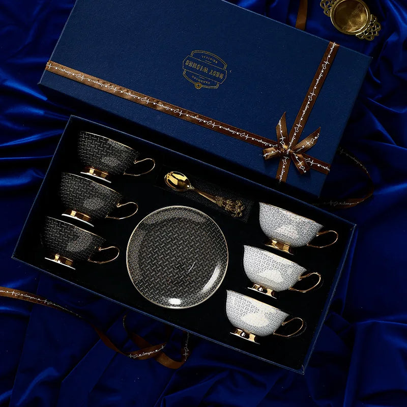 Tea set with black and gold cups and saucers in a decorative box on a blue satin background.