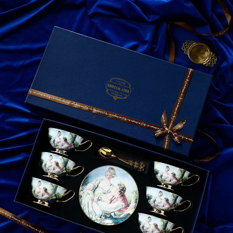 Set of tea cups and saucers with a decorative plate in a gift box on a blue satin background.