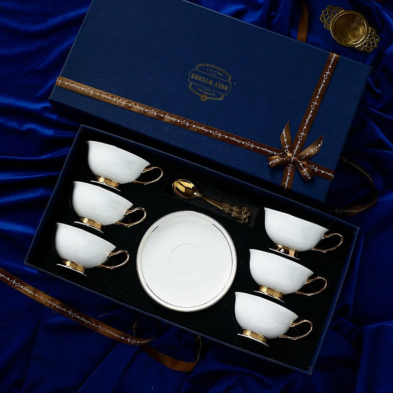 Ceramic tea set with gold accents in a decorative box on a blue fabric background