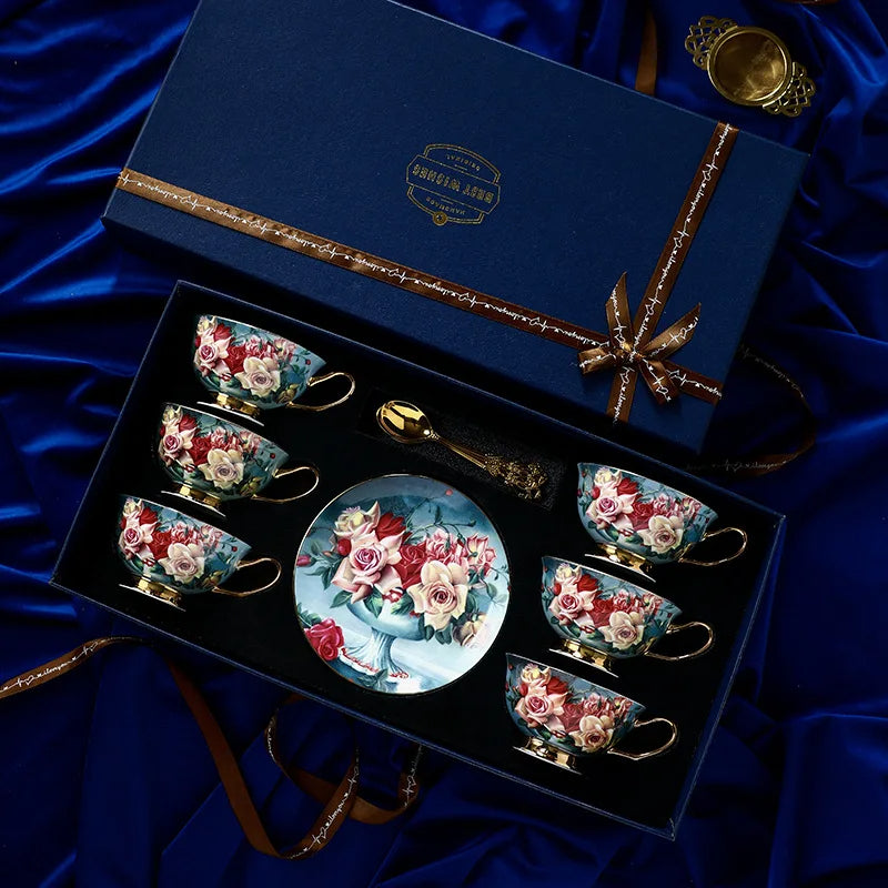 Set of decorative teacups and saucers in a gift box with floral designs on a blue satin background.