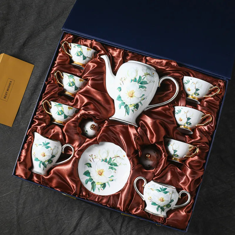 Ceramic tea set with floral designs in a decorative box on a dark surface.